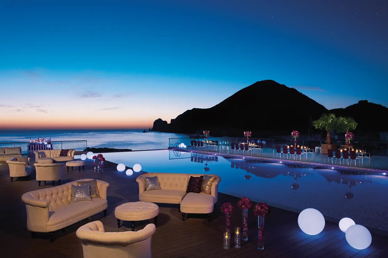 Sunset gala dinner and event setup by the infinity pool at Breathless Cabo San Lucas overlooking the ocean.