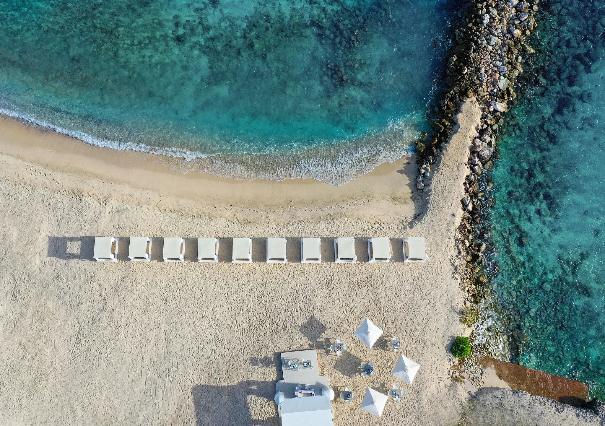 Aerial view of Zoëtry Curaçao’s private beach with cabanas and clear Caribbean waters.