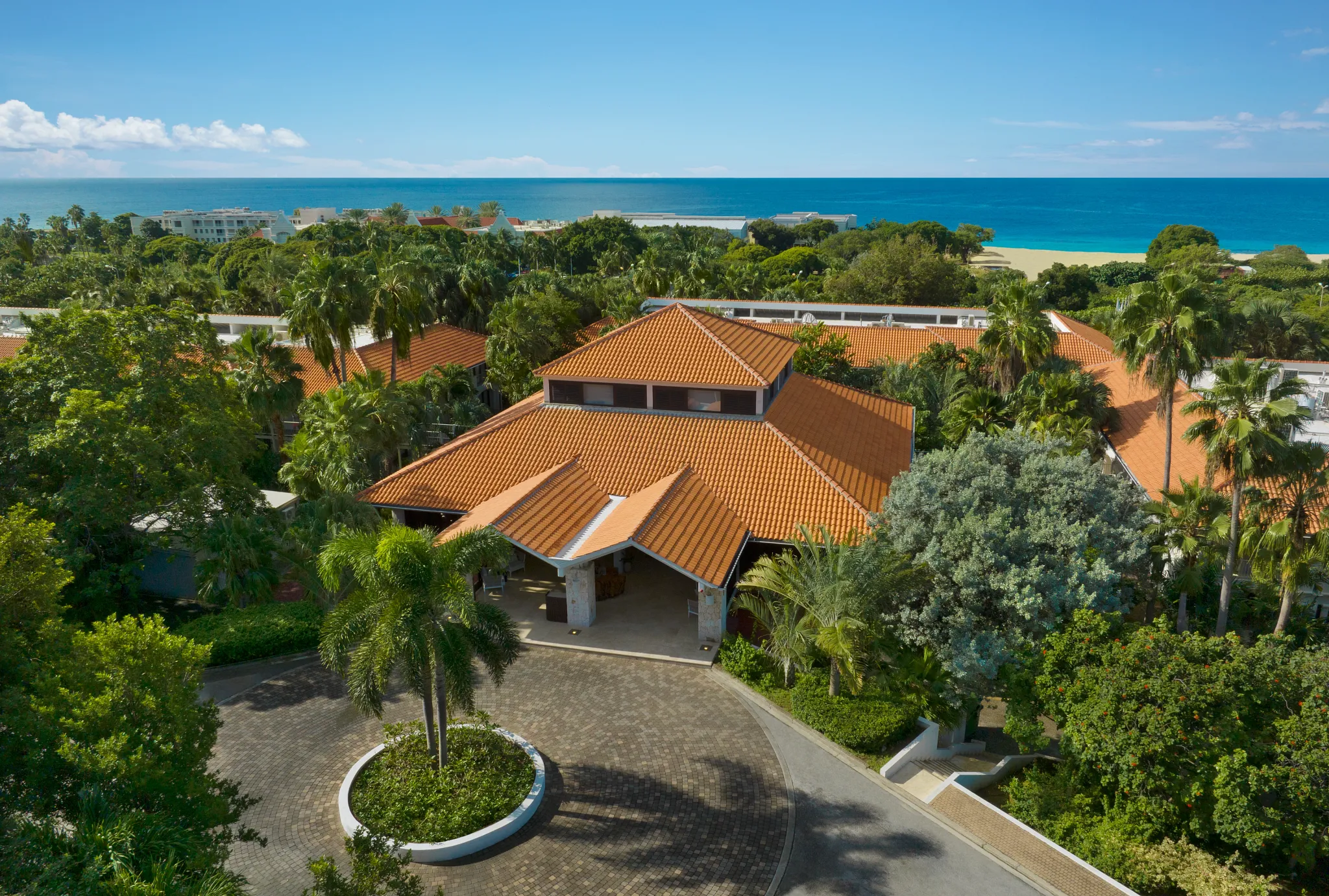 Aerial view of Zoëtry Curaçao Resort & Spa surrounded by lush greenery with the Caribbean Sea in the distance.